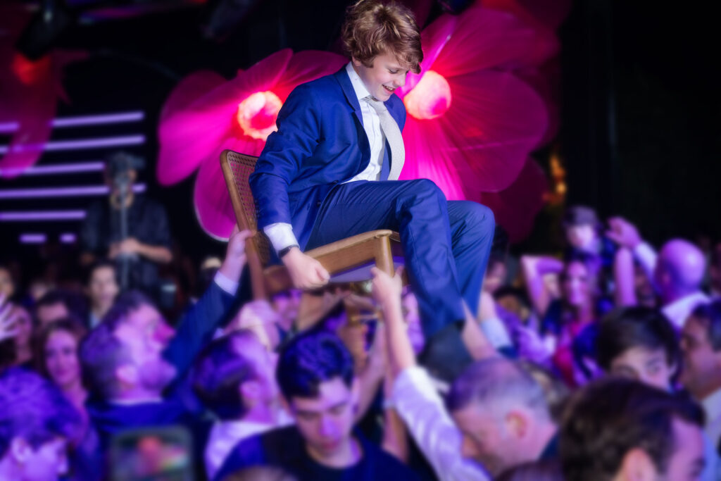 Menino na cadeira com pessoas comemorando o bar mitzvah